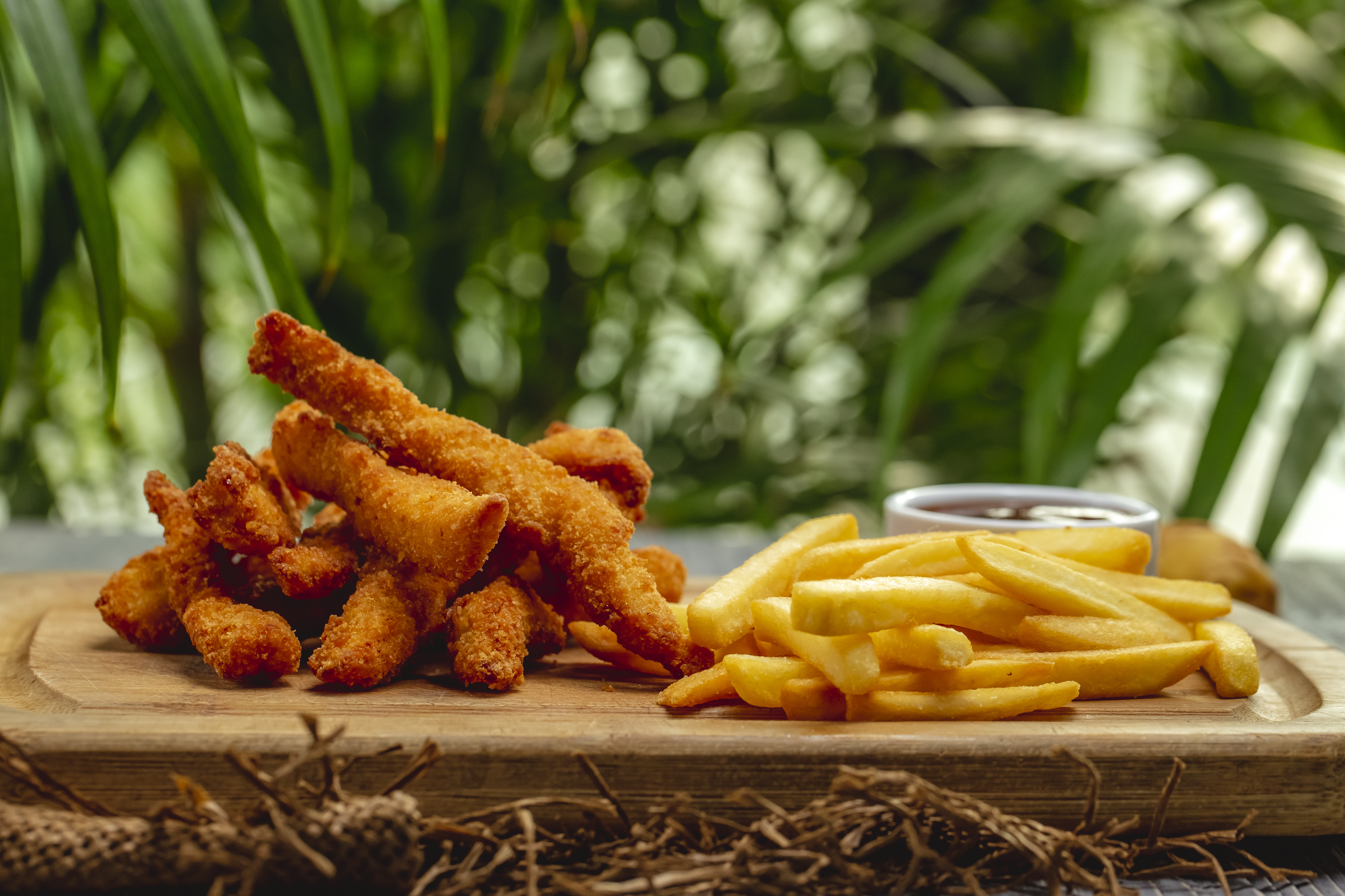 tiras-de-pechuga-de-pollo-empanadas-fritas-con-salsa-de-tomate-y-papas-fritas-en-una-tabla-de-madera